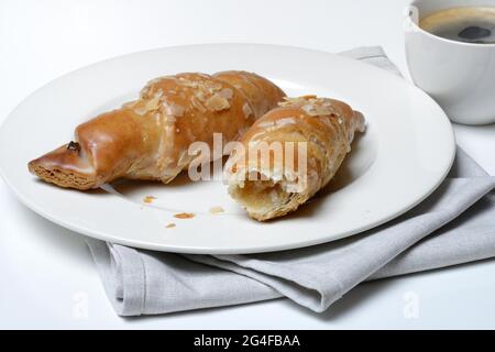 Mandelcroissant auf Teller mit Kaffeetasse, Deutschland Stockfoto