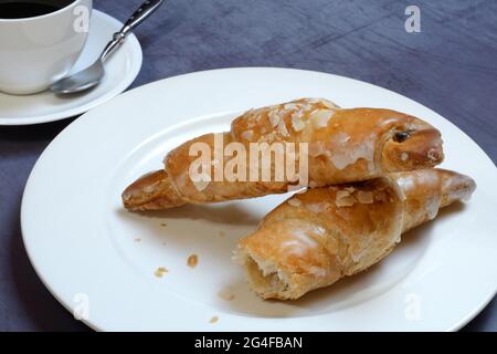 Mandelcroissant auf Teller mit Kaffeetasse, Deutschland Stockfoto