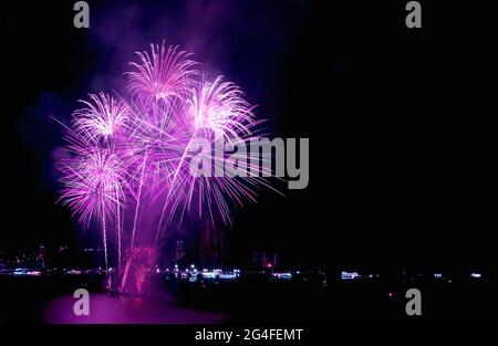 Atemberaubendes purpurrosa Feuerwerk, das über dem Hafen in den Nachthimmel explodiert Stockfoto