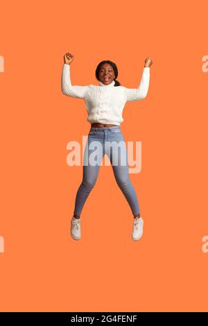 Großer Gewinn. Aufgeregte Afroamerikanische Frau Feiert Erfolg Beim Sprung In Der Luft Stockfoto