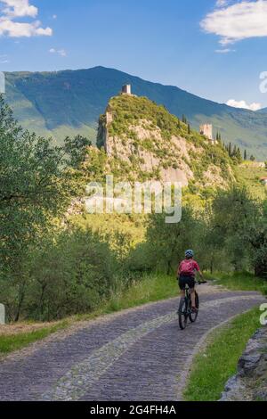 Aktive ältere Frau auf ihrem elektrischen Mountainbike in den Bergen des Gardasees zwischen den Olivenhainen des Schlosses Arco in der Nähe von Riva del Garda, Italien Stockfoto