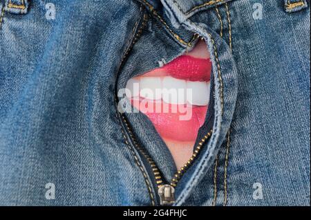 Weiblicher Mund hinter dem offenen Reißverschluss der Denim-Hose Stockfoto