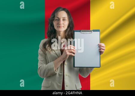 Studieren in Kamerun schöne Frau, die ein Blatt Papier in den Händen hält. Mädchen auf dem Hintergrund der Flagge von Kamerun. Stockfoto