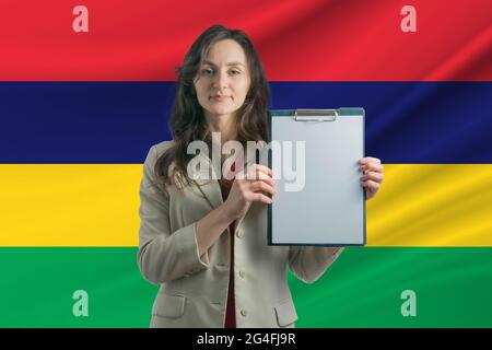 Studieren Sie in Mauritius. Schöne Frau, die ein Blatt Papier in den Händen hält. Mädchen auf dem Hintergrund der Flagge von Mauritius. Stockfoto