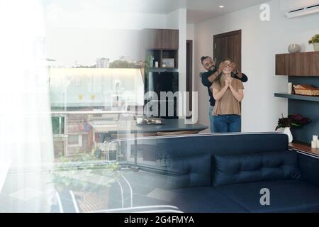 Aufgeregt junger Mann, der die Augen der Freundin verdeckt, als er ihre neue Wohnung zeigte, die er gemietet hatte Stockfoto