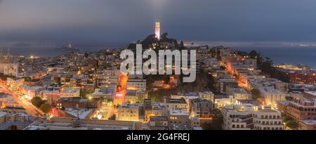 Der Coit Tower wurde für den LGBT Pride in San Francisco in Pink beleuchtet, mit nebligen Wolken über Telegraph Hill und North Beach Districts Stockfoto