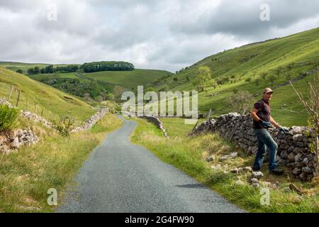 Trockener Stein waller bei der Arbeit im Yorkshire Dales National Park mit dem berühmten steilen Fahrradhügel des Park Rash als Hintergrund, Großbritannien Stockfoto