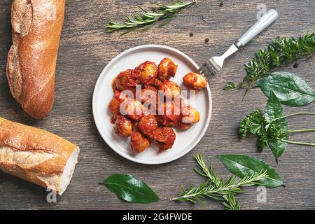 Pilze, Brot und Kräuter nach griechischer Art - Lorbeerblätter, Petersilie, Rosmarin, Thymian auf dunklem Holzgrund, Draufsicht Stockfoto