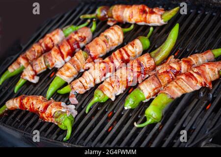 Jalapeno knallt auf das Brennen, grillen. Würzige Paprika, gefüllt mit Frischkäse und in Speck eingewickelt. Draufsicht mit selektivem Fokus. Stockfoto