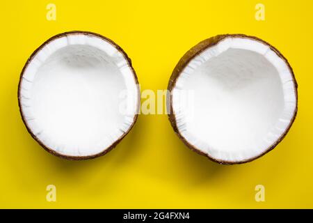 Zwei Hälften Kokosnuss auf gelbem Hintergrund. Draufsicht Stockfoto