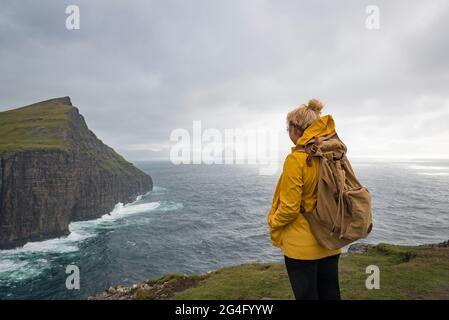 Eine Frau, die das Meer entlang des Traelanipa Wanderweges am See Sorvagsvatn auf der Insel Vagar auf den Färöer Inseln betrachtet Stockfoto