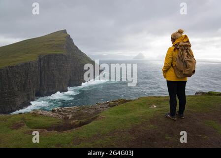 Eine Frau, die das Meer entlang des Traelanipa Wanderweges am See Sorvagsvatn auf der Insel Vagar auf den Färöer Inseln betrachtet Stockfoto