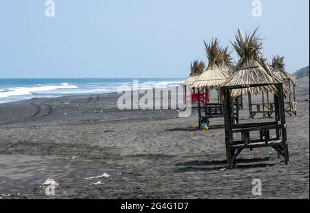 Traditionelle Sonnenschutzhütten am Strand, ausgewählter Fokus in Pantai Dewa Ruci Purworejo, Indonesien, mit verschwommenem blauen Indischen Ozean im Hintergrund Stockfoto