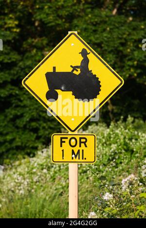 Carnation, WA, USA - 18. Juni 2021; Warnschild für den ländlichen Betrieb mit einem Bauern auf einem schwarzen Traktor auf einem gelben Diamantschild Stockfoto