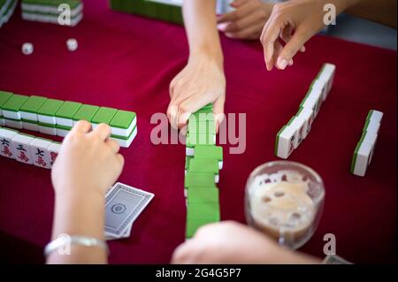 Menschen spielen zu Hause Mahjong traditionelles chinesisches Brettspiel auf einem roten Tisch Stockfoto