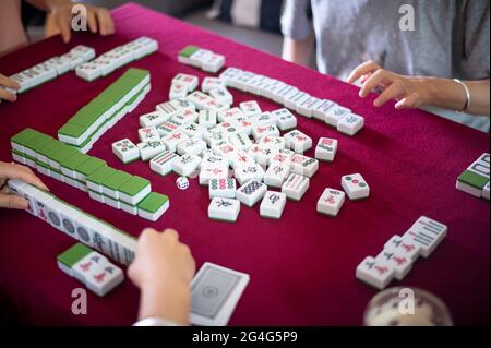 Menschen spielen zu Hause Mahjong traditionelles chinesisches Brettspiel auf einem roten Tisch Stockfoto