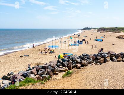 Sonniger Strand voller Urlauber von Klippen in Happisburgh an der Küste von Norfolk, Großbritannien Stockfoto