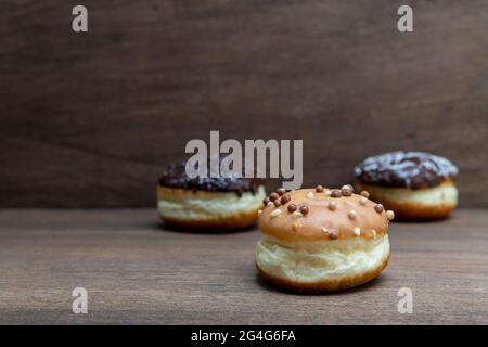 Köstliche glasierte Schokoladendonuts auf Holzhintergrund Stockfoto