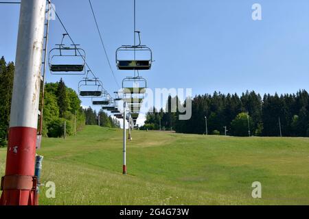 Blick auf die Stühle des Skilifts in verlassenen Skigebiet , Jasenska dolina, in der Region Turiec, Slowakei im Sommer. Hügel ist mit Gras bedeckt. Stockfoto