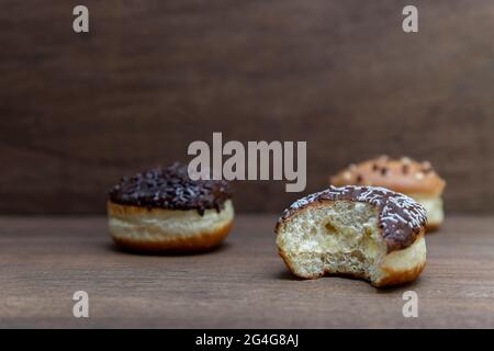 Köstliche glasierte Schokoladendonuts auf Holzhintergrund Stockfoto