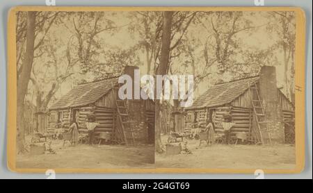 Ein Stereograph mit dem Titel „Plantation Scene; Folks All Home“, gedruckt von J. N. Wilson aus Savannah, Georgia. Die Albuminabzüge zeigen sechs (6) nicht identifizierte afroamerikanische Kinder im Hof vor einem Blockhaus mit einem Ziegelkamin. Ein Mädchen steht in der Nähe der Mitte mit ihren Händen in einem hölzernen Waschbecken auf einem Ständer. Ein Junge steht zu ihrer rechten Seite mit seinem Rücken an der Ecke des Gebäudes und hält einen großen vollen Korb auf seinem Kopf. Zwei jüngere Kinder sitzen auf einer Bank außerhalb des Gebäudes im Hintergrund. Zwei Kleinkinder sitzen auf der linken Seite des Rahmens, eines auf dem Rad eines kleinen Holzes Stockfoto