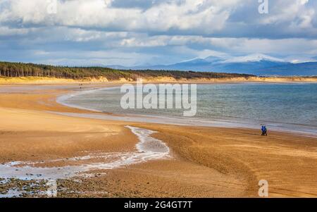 Newborough Beach bei Ebbe von Llanddwyn Island mit den schneebedeckten Bergen von Snowdonia im Hintergrund, Isle of Anglesey, Nordwales Stockfoto