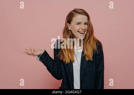 Lachende junge Frau mit kippender Hand und zuckenden Schultern Stockfoto