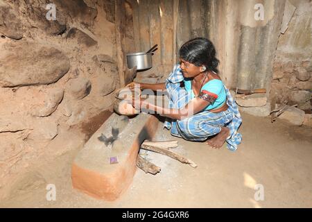 LANJIA SAORA STAMM. Stammesfrau, die Ragi-Essen mit Schlammtopf und traditionellem Schlammherd in der Küche zubereitet. Puttasingh Dorf in Odisha, Indien Stockfoto