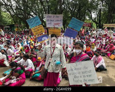 Kolhapur, Maharashtra, Indien. Juni 2021. Eine akkreditierte Gesundheitsarbeiterin hält ein Plakat, auf dem sie für ihre Rechte kämpft. Mehr als 2000 ASHA-Arbeiter protestierten heute vor dem Bezirksrichter in Kolhapur für ihre drei Monate ausstehenden Gehälter und andere Forderungen. Akkreditierte Mitarbeiter im Gesundheitswesen (ASHA) sind Mitarbeiter an vorderster Front in dieser Pandemie. Diese mutigen Menschen sind mit nicht-COVID- und COVID-Aufgaben überfordert. Sie riskieren ihr Leben mit unzureichender Sicherheitsausrüstung und nur 33 INR als täglichen COVID-Anreiz. Die siebzigtausend ASHA-Arbeiter aus Maharashtra befinden sich auf unbestimmte Zeit Stockfoto