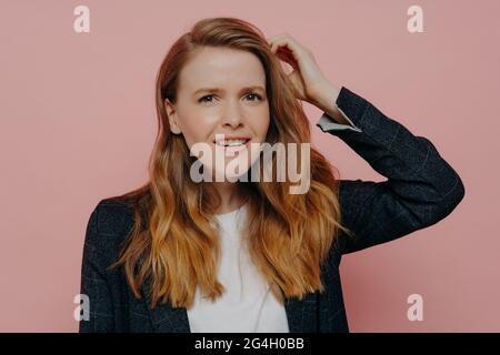 Verwirrte junge Frau, die beim Berühren des Kopfes denkt Stockfoto