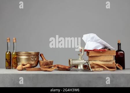 Kochmütze, alte Kochbücher und alte Küchenutensilien auf dem Küchentisch. Speicherplatz kopieren. Stockfoto