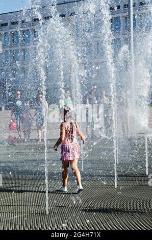 Menschen am Brunnen, abnorme Hitze in Russland. Ein kleines Mädchen läuft unter den kalten Wasserstrahlen. Uljanowsk, Russland, 19. Juni 2021 Stockfoto