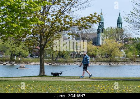 Lachine, CA - 15. Mai 2021: Menschen gehen mit Hund auf dem Radweg des René Lévesque Parks Stockfoto