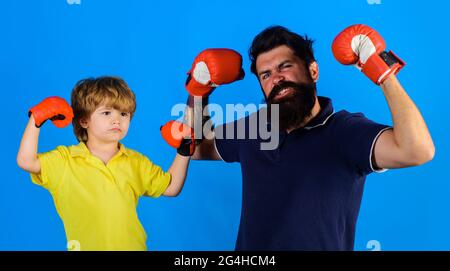 Kleiner Junge Sportler beim Boxtraining mit Trainer. Kind Junge macht Boxings Übung mit Vater. Vater und Sohn mit Boxhandschuhen. Stockfoto