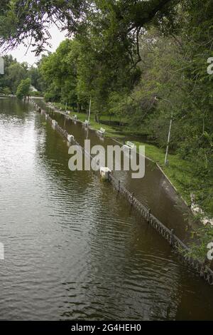 Öffentlicher Park, der von Regen durchnässt ist. Wasser protokolliert Park.Wet Bänke. Park gefüllt mit Wasser nach Regen.leeren Park nach starkem Regen. Stockfoto