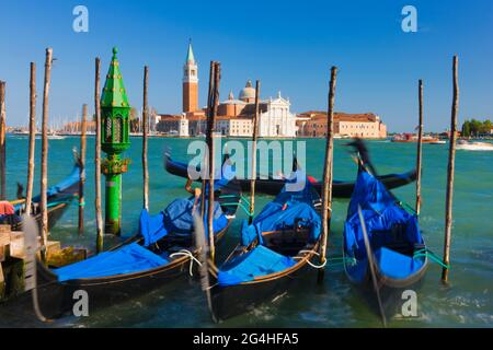 Gondelboote legen entlang des Markukanals in Venedig mit San Giorgio Maggiore und dem Markusturm in der Ferne, Italien, fest Stockfoto