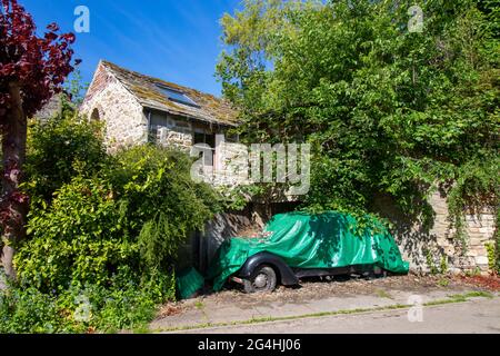 Altes Auto mit grüner Plane vor dem Steinhaus in der Nähe von Hexham Northumberland Stockfoto