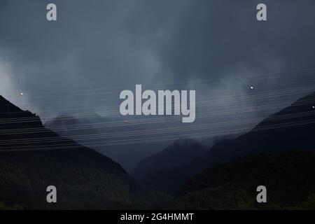 Stromleitungen vom Kraftwerk Manapouri, gegen graue Wolken, Lake Manapouri, Fiordland National Park, South Island, Neuseeland Stockfoto