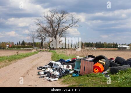 LESZNO, POLEN - 03. Mai 2021: Illegale Mülldeponie auf Feldern, auf der Straße. Altelektronik und Kunststoff. Zerstören Sie die Natur Stockfoto