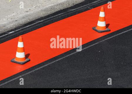 Rote und weiße Pylons auf einem frisch rot markierten Radweg Stockfoto