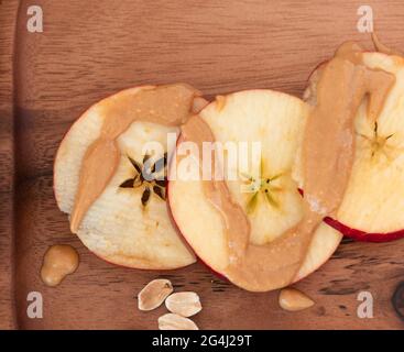 Draufsicht auf Apfelscheiben mit Erdnussbutter auf Holzplatte Stockfoto
