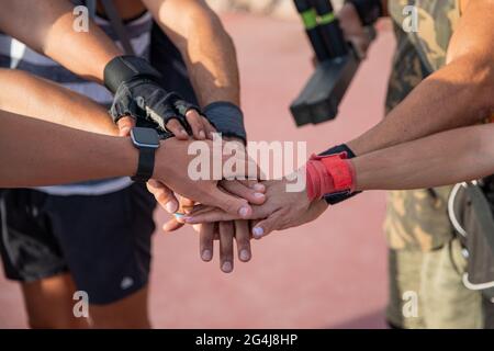 Eine Gruppe von Sportlern legt ihre Hände übereinander während eines Work-out, eines Teams und einer Einheit aus der Nähe auf eine Gruppe von Händen Stockfoto