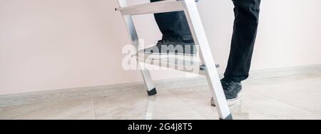 Nahaufnahme Arbeiter Füße auf der Leiter klettern nach oben gegen die Wand mit Kopierraum Stockfoto