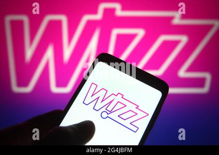 Auf dieser Abbildung ist ein Wizz Air-Logo einer ungarischen Billigfluggesellschaft auf einem Smartphone und einem pc-Bildschirm zu sehen. Stockfoto