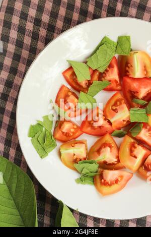 Viele saftige Tomaten in Scheiben geschnitten, Tomaten auf weißem Teller geschnitten, Draufsicht Stockfoto