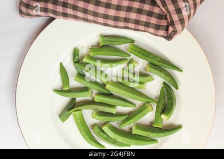 Draufsicht auf Stapel von frischen grünen Okra auf Holzplatte isoliert auf weißem Hintergrund. Gesundes Gemüse und Pflanzen. Gängige Zutaten für das Kochen in Bangladesch Stockfoto