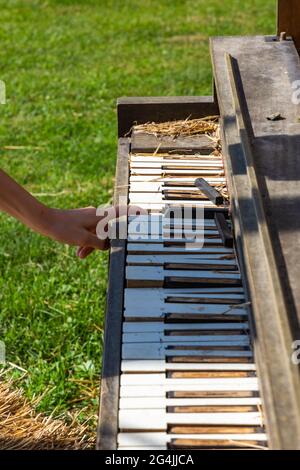 Ein Mädchen gibt vor, eine Notiz auf ein dekreptes Klavier von P. A. Starck zu schlagen. Stockfoto