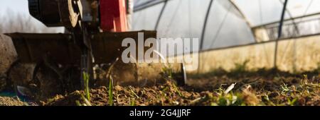 Der Bauer bereitet mit einem Cutter den Boden für den Sommergarten vor Stockfoto