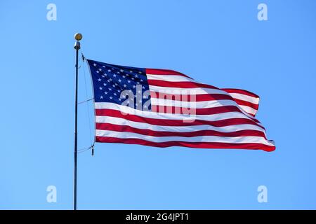 USA-Flagge. Die Flagge der Vereinigten Staaten, die im Wind wunderschön an einer Stange winkt. Blauer Himmel. Stockfoto