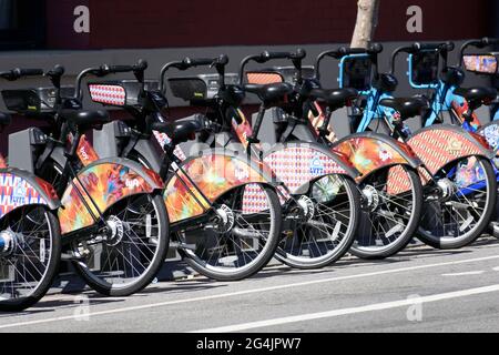 Eine Gruppe von bunten Lyft E-Assist Bay Wheels Classic Bikes, die in einer Reihe an der Outdoor-Fahrradstation geparkt sind. - San Francisco, Kalifornien, USA - 2021 Stockfoto